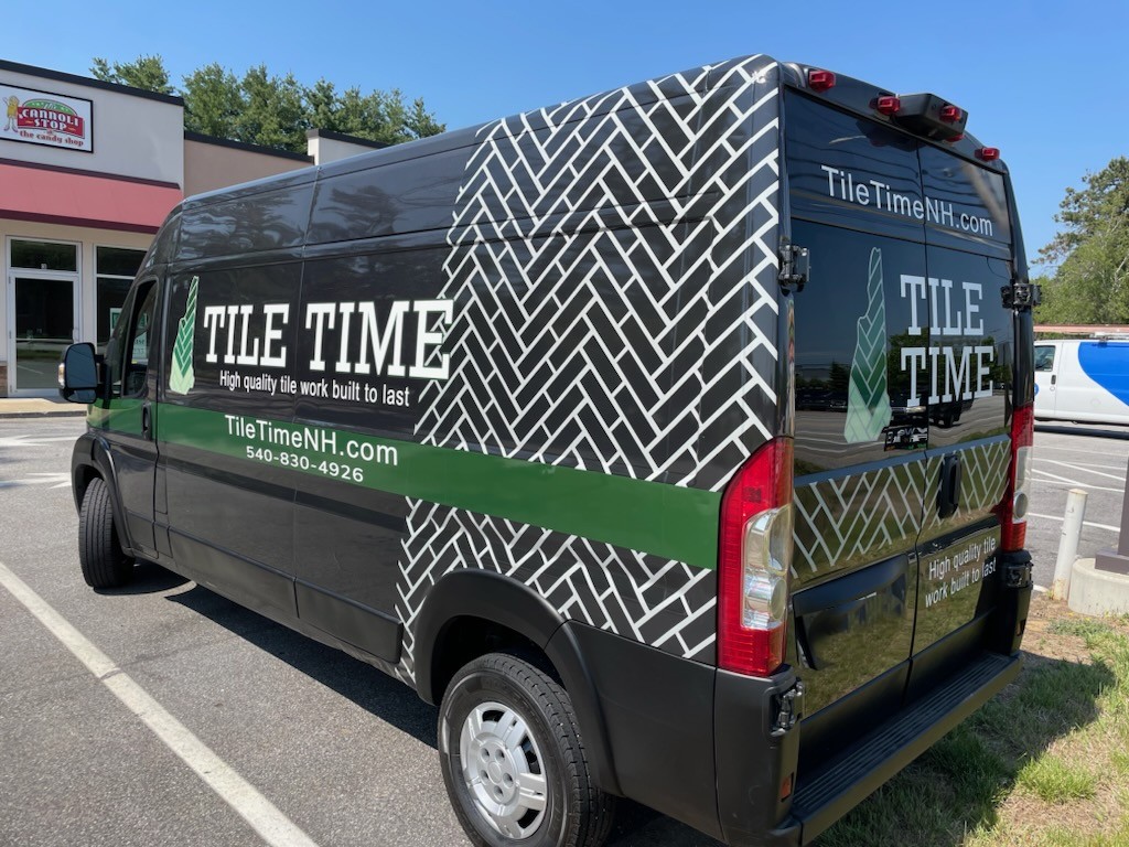 Black commercial van with custom vinyl graphics and letter decals for business fleet branding. Premium mobile installation available for dealerships.