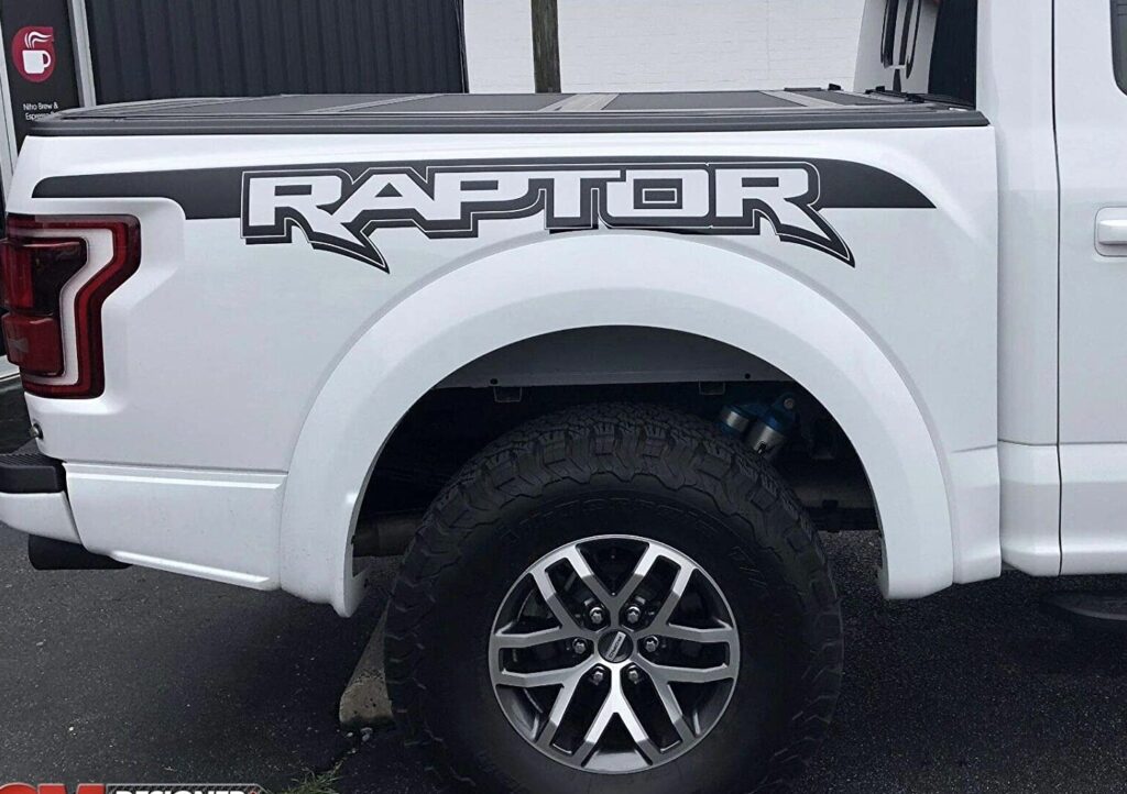 Black Raptor graphic decal on a white Ford truck, featuring custom vinyl wrap and truck graphics installed by a premium dealer service.